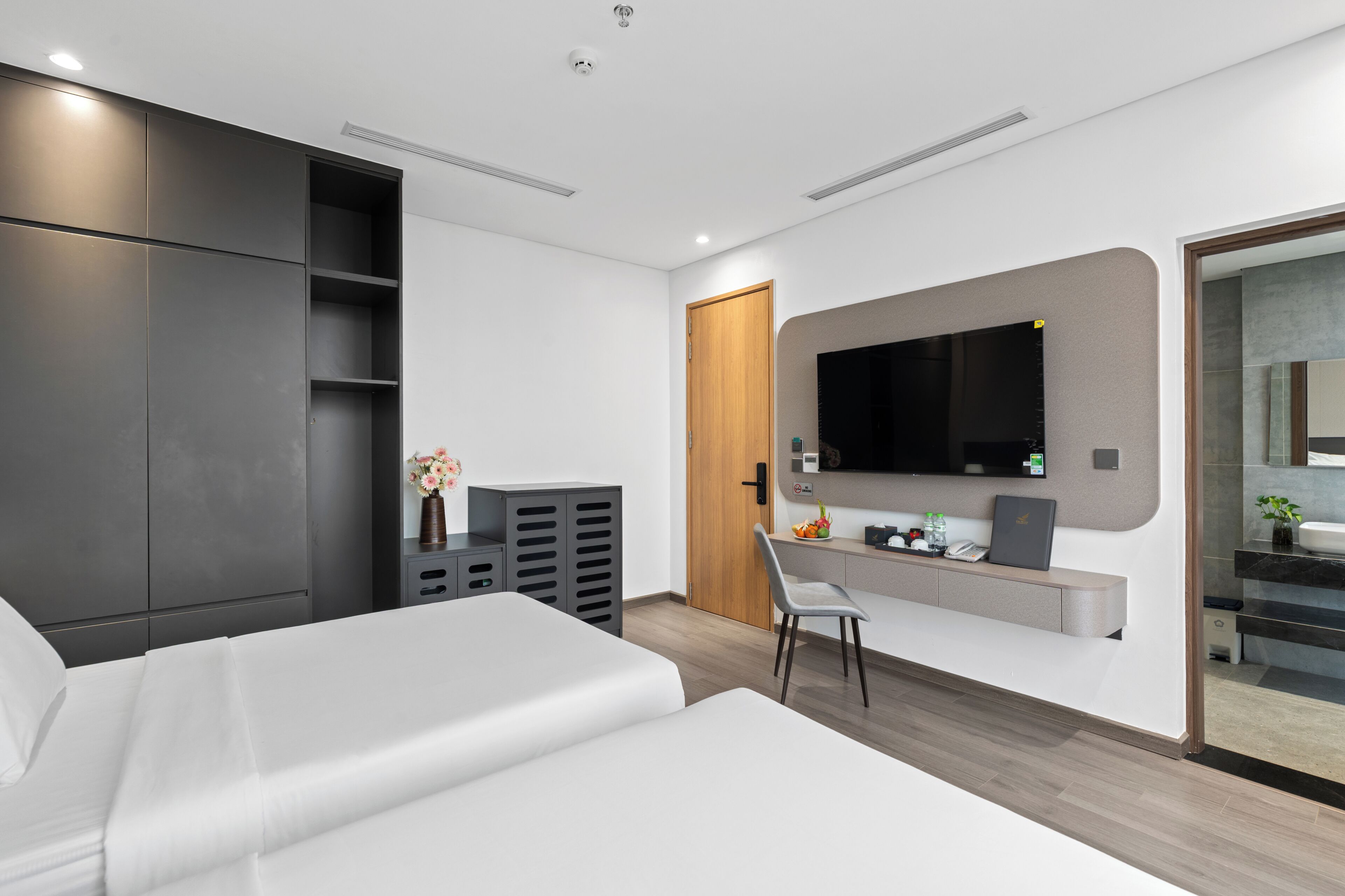 A modern hotel room with a bed, a desk, a TV, and a wardrobe.