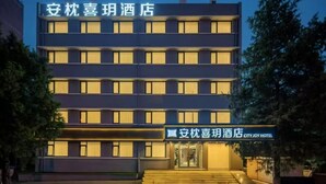 Un edificio de hotel de varios pisos con ventanas iluminadas y un cartel en chino e inglés.