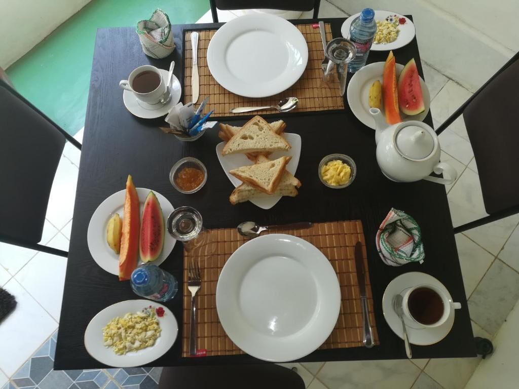 A dining table with plates, cups, and cutlery, arranged with food and drinks.