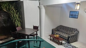 A dining area with a table and chairs, a sofa, and a potted plant. - Velvet Paradise (Dambulla)