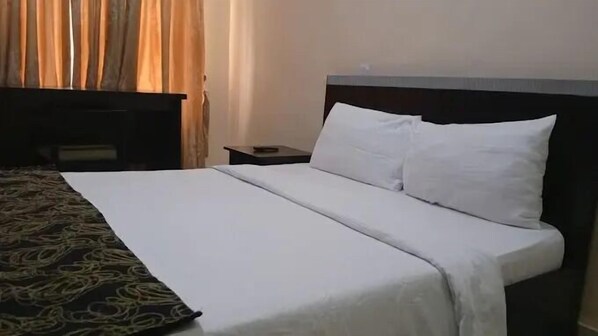 Una habitación de hotel con una cama, una mesita de noche y un escritorio.