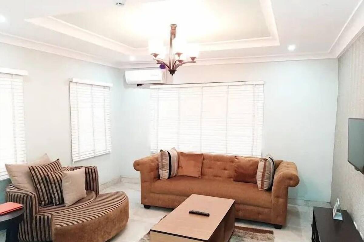 A living room with a brown sofa, striped armchair, and a small wooden coffee table.