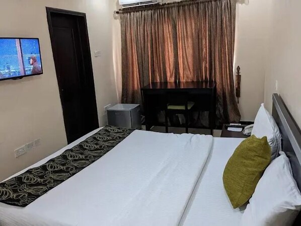 A hotel room with a bed, a desk, and a television on the wall.