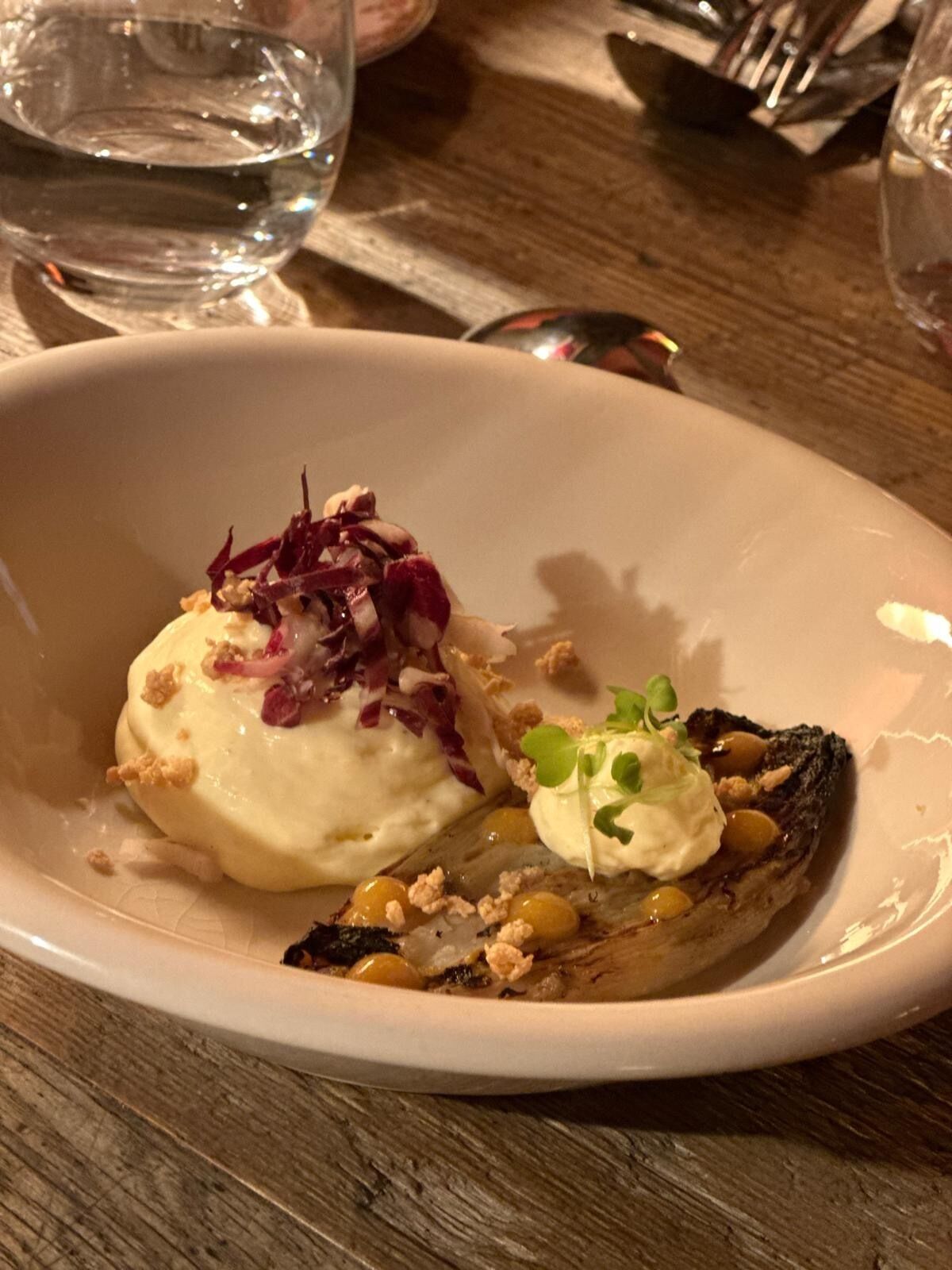 A dessert plate with a scoop of ice cream, a piece of grilled fruit, and garnishes.