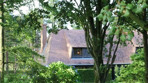 A house with a sloped roof, surrounded by lush greenery and trees. - Auberge Bout de Bois (Saint-Jouin-Bruneval)