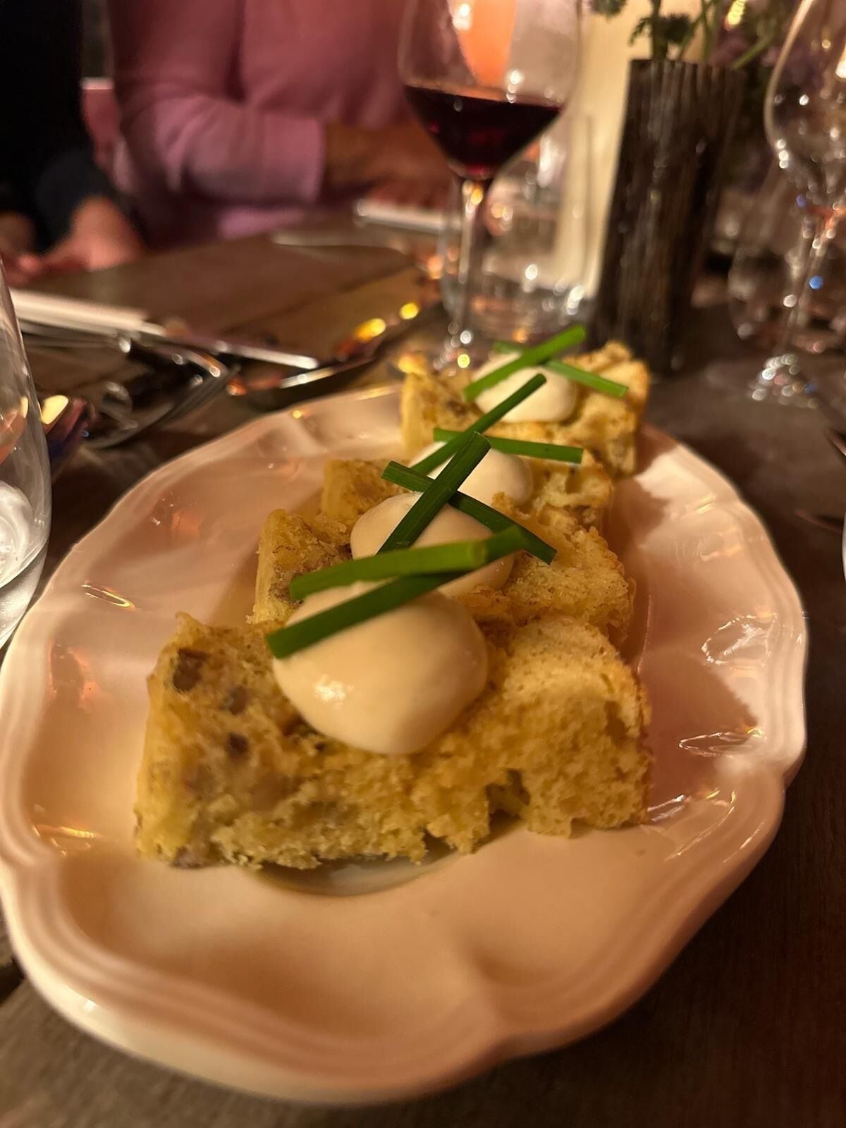 A plate with a dish consisting of bread and a poached egg garnished with chives.