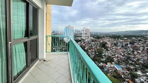A balcony with a city view, a railing, and a building with "REALTY NETWORK BROKERAGE" signage in the background. - CityHouse A (Cebu)