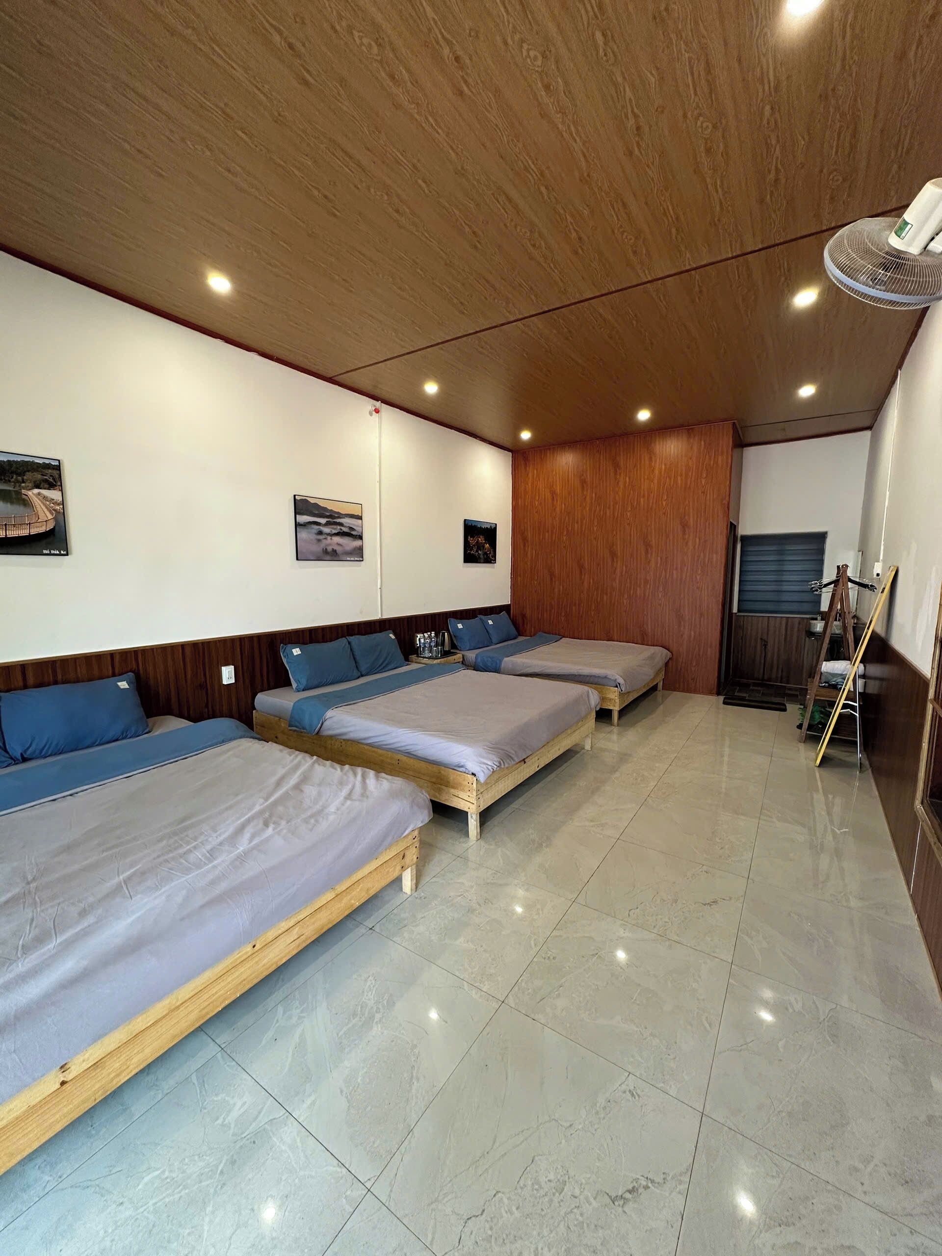 A hotel room with three wooden beds, a wooden ceiling, and a tiled floor.