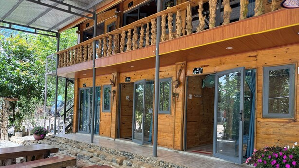 Un edificio de madera con balcón, sendero de piedra y bancos de madera.