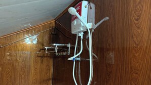 Una ducha con cabezal de ducha de mano y panel de control en la pared.