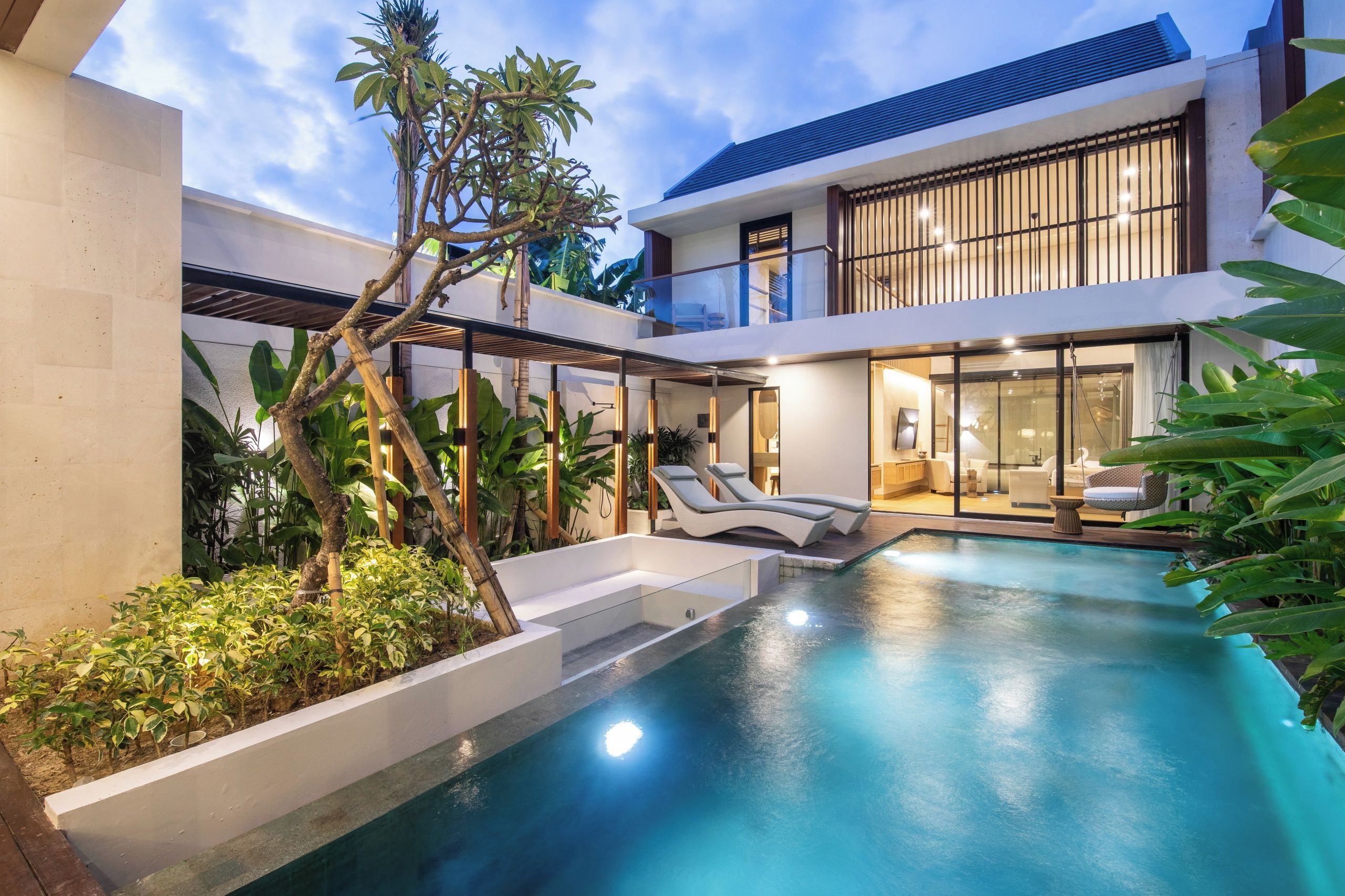 A modern house with a swimming pool, outdoor seating, and lush greenery.