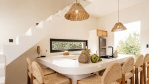 A kitchen with a large island, wicker chairs, and a view of greenery outside. - Boho Retreat 3BR Enclosed Lounge 5min Beach (Canggu)