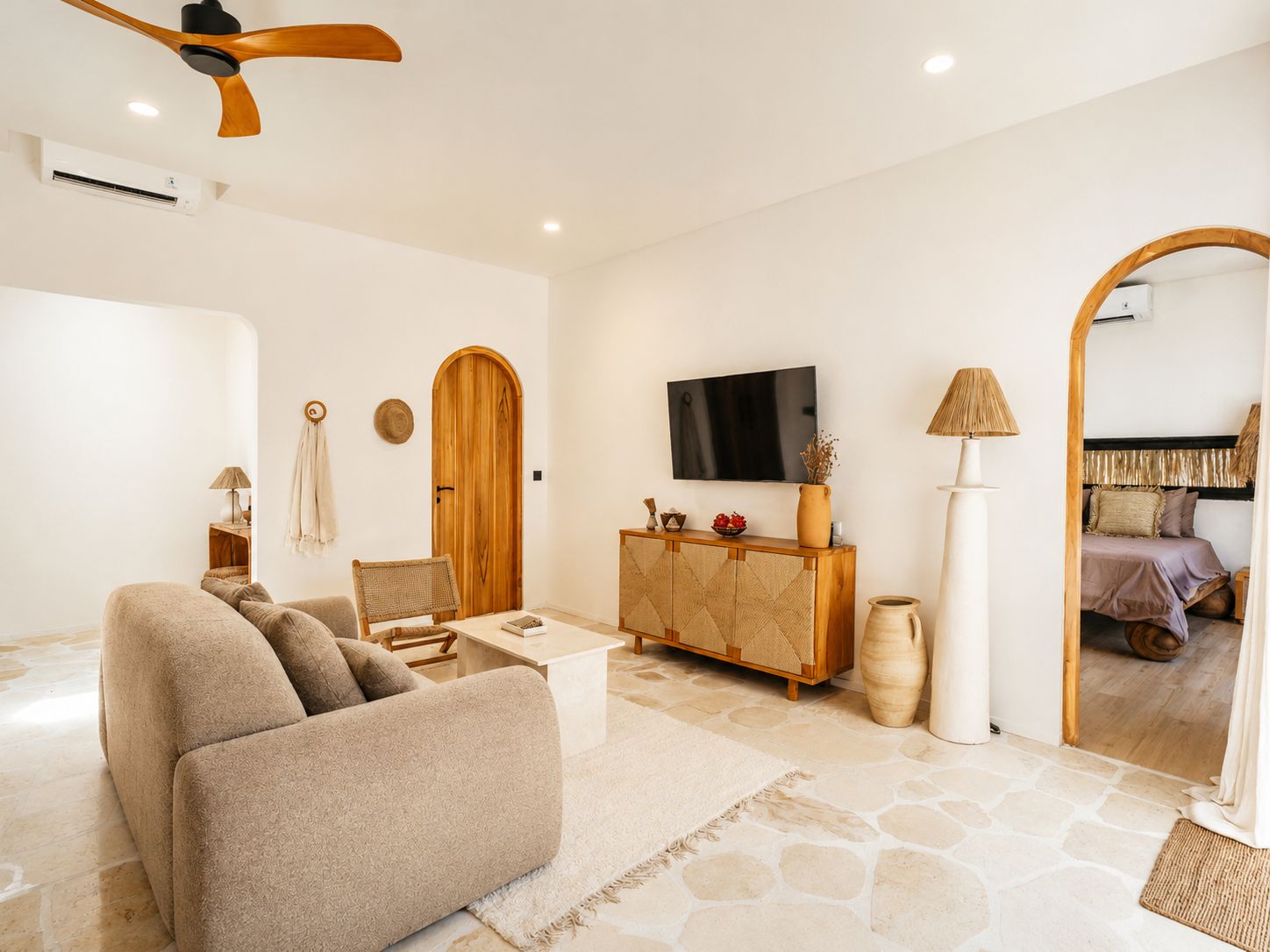A living room with a sofa, a TV, a wooden cabinet, and a mirror.
