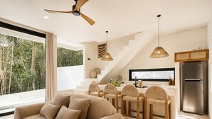 A modern kitchen with a dining area, a sofa, and a staircase. - Boho Retreat 3BR Enclosed Lounge 5min Beach (Canggu)
