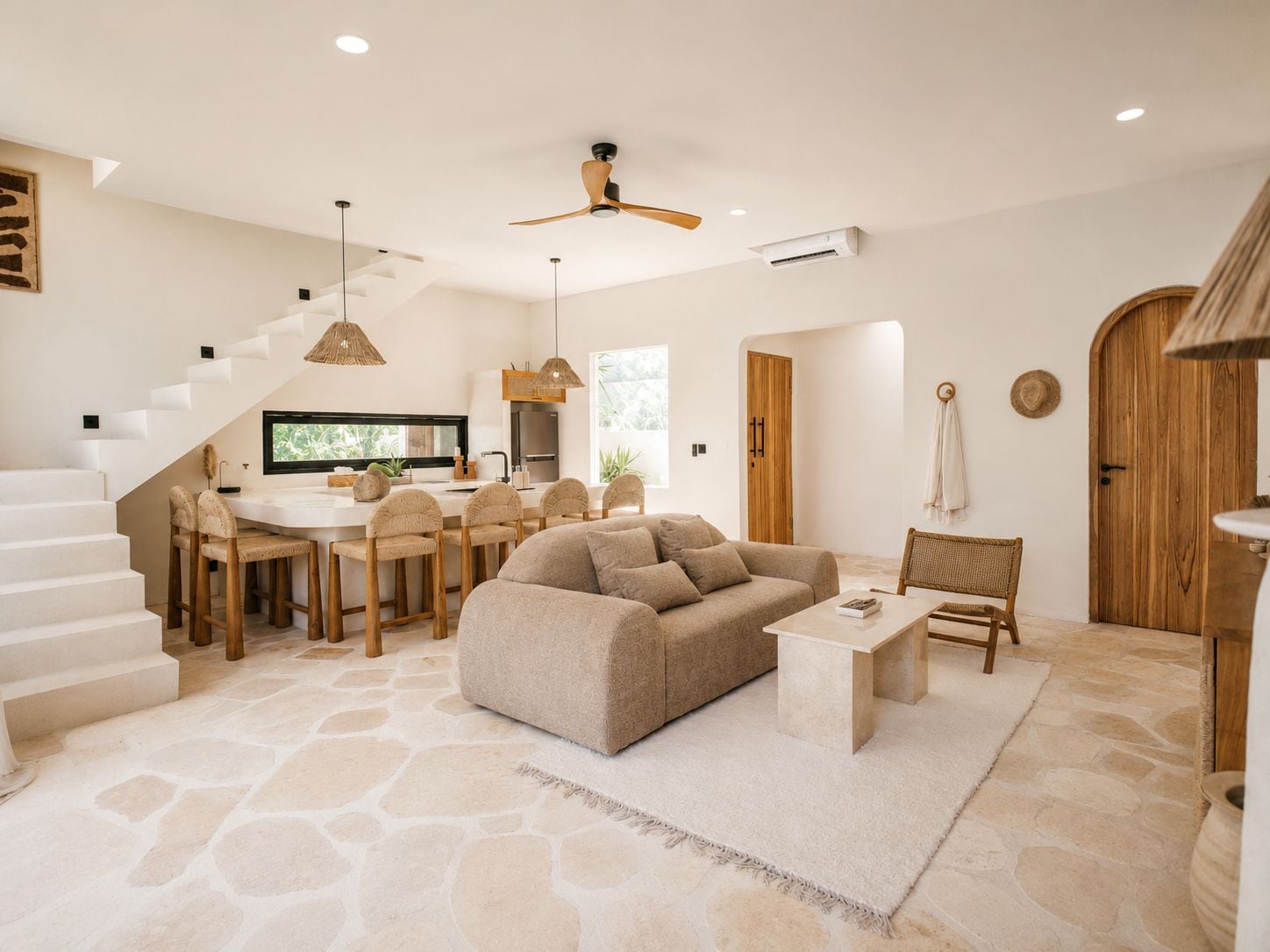 A modern interior with a stone floor, a sofa, a dining area, and a staircase.