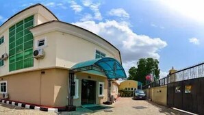 A two-story building with a curved facade, a covered entrance, and a gated driveway. - Celia's Hotel and Suites  (Abeokuta)