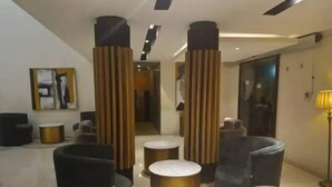 A modern lobby with black and grey sofas, a gold coffee table, and a tall pillar. - IBD Hotel and Suites (Abeokuta)