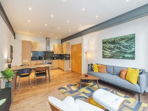 A modern living space with a kitchen, dining area, and a sofa with cushions. - The Shoreditch Warehouse, by Veeve (London)