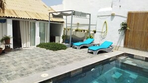 A pool area with two lounge chairs, a covered seating area, and a small garden. - Atypical house with swimming pool (Douaouda)
