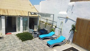A sunlit outdoor area with two lounge chairs and a covered seating area. - Atypical house with swimming pool (Douaouda)