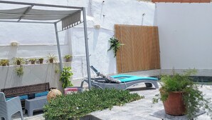 A covered outdoor seating area with a pool, potted plants, and a wooden panel wall. - Atypical house with swimming pool (Douaouda)