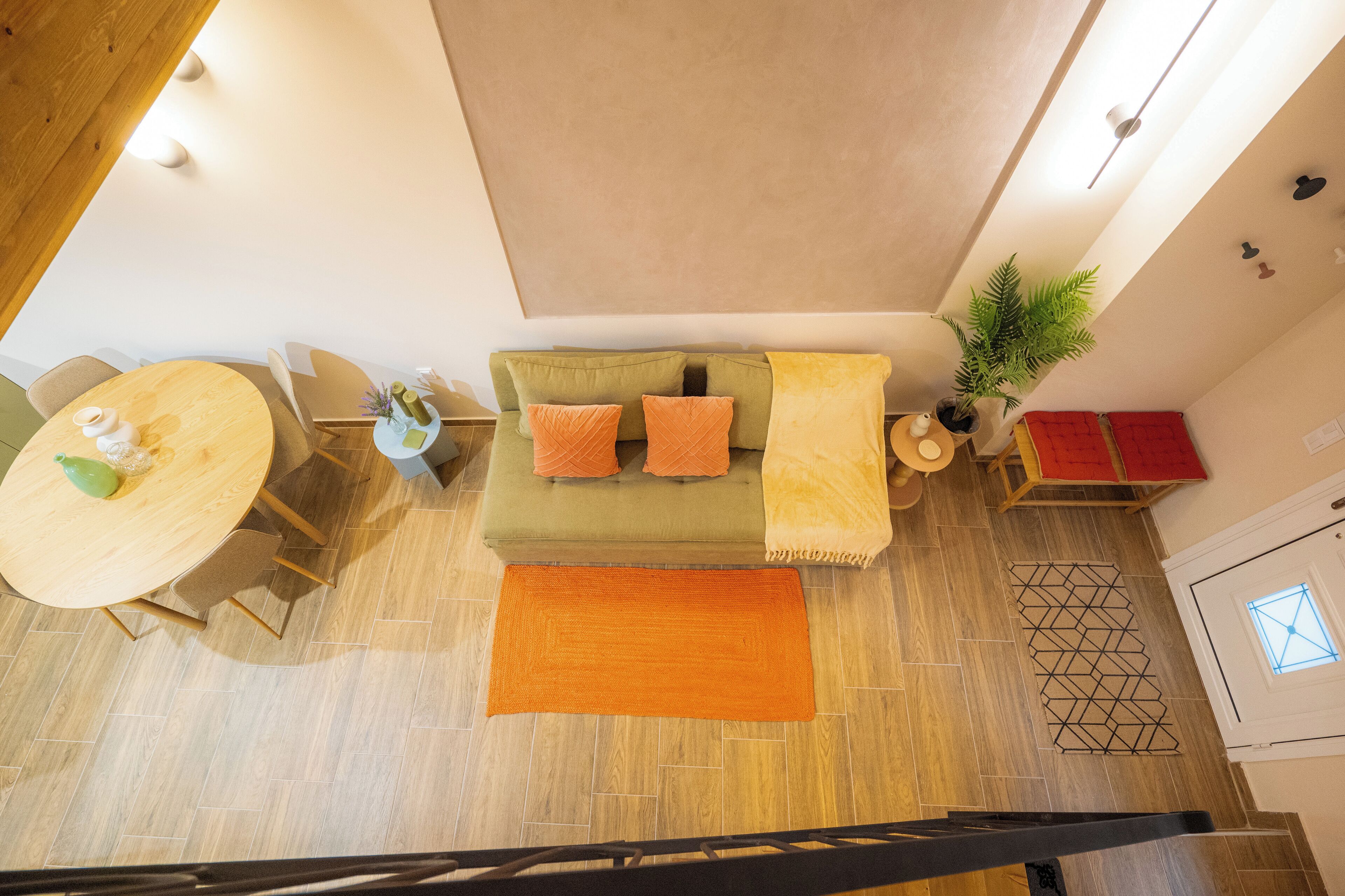 A modern living room with a sofa, a dining table, and a staircase.