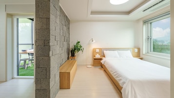 Un dormitorio moderno con una cama grande, mesitas de noche, una lámpara de pie y vistas al exterior a través de una ventana.