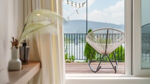 Un balcon avec un fauteuil en osier, une plante et une vue sur les montagnes.