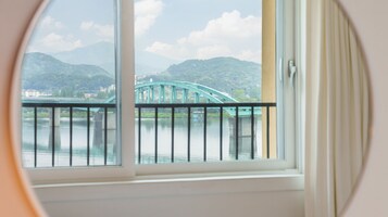 A view through a window of a bridge over water, with mountains in the background.