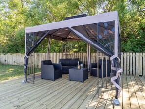 An outdoor patio with a covered seating area, including a sofa and two side tables.