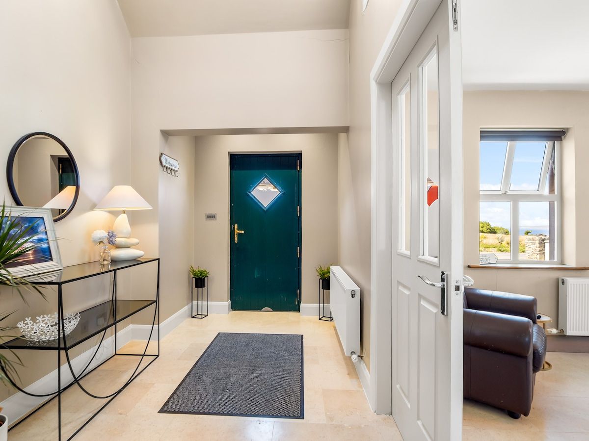 A modern interior with a reception desk, a dark green door, and a seating area with a view.