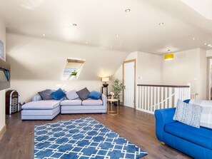 A modern living room with a sectional sofa, a blue couch, and a patterned rug.