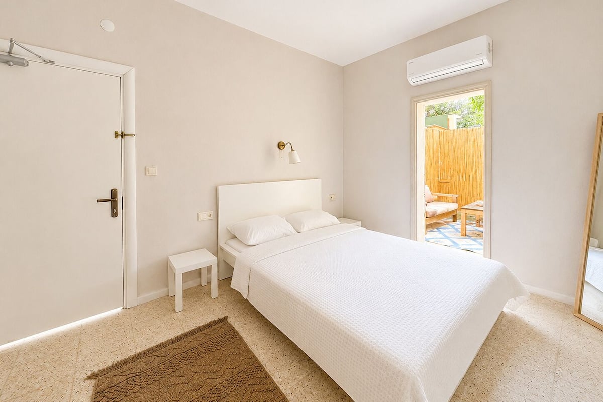 A bedroom with a bed, bedside table, and a window.