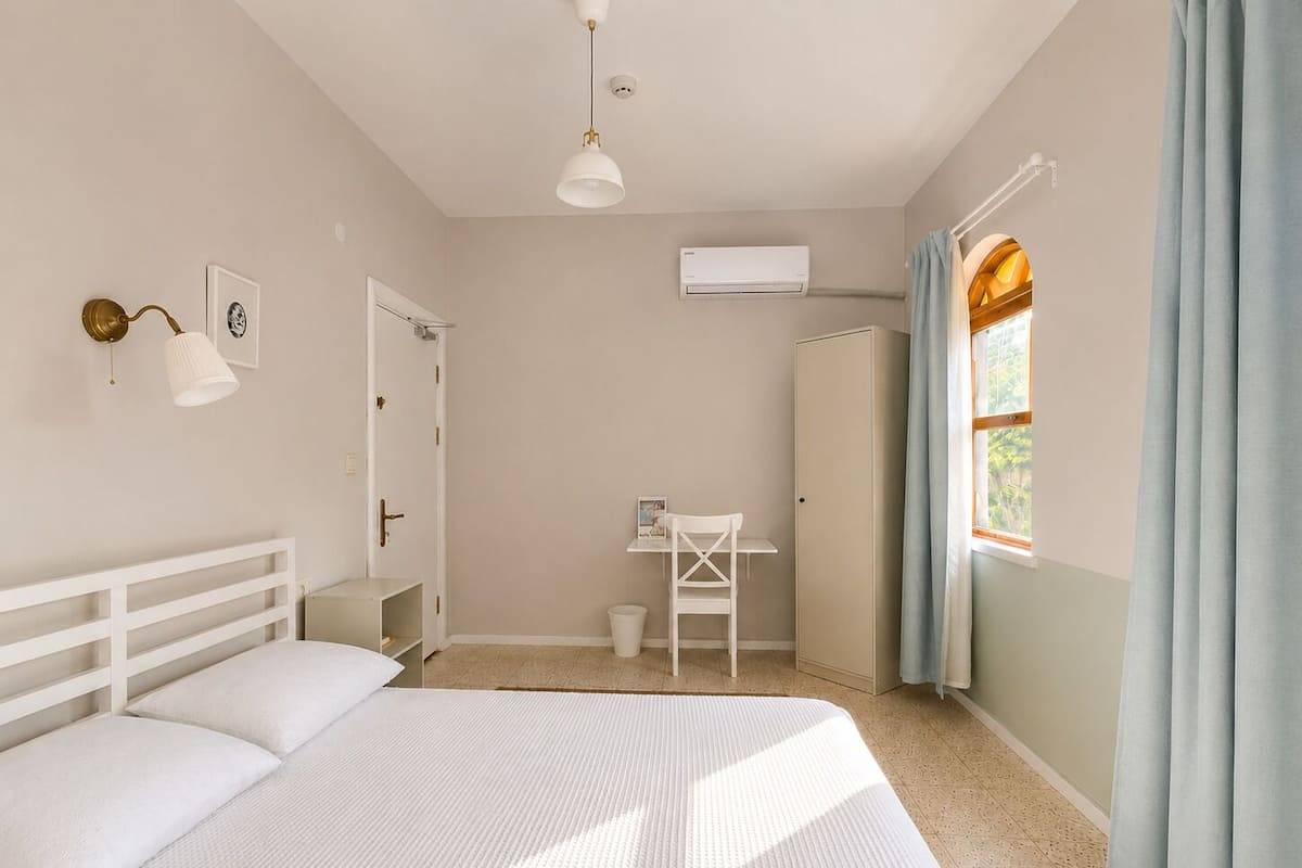 A bedroom with a bed, a desk, and a wardrobe.