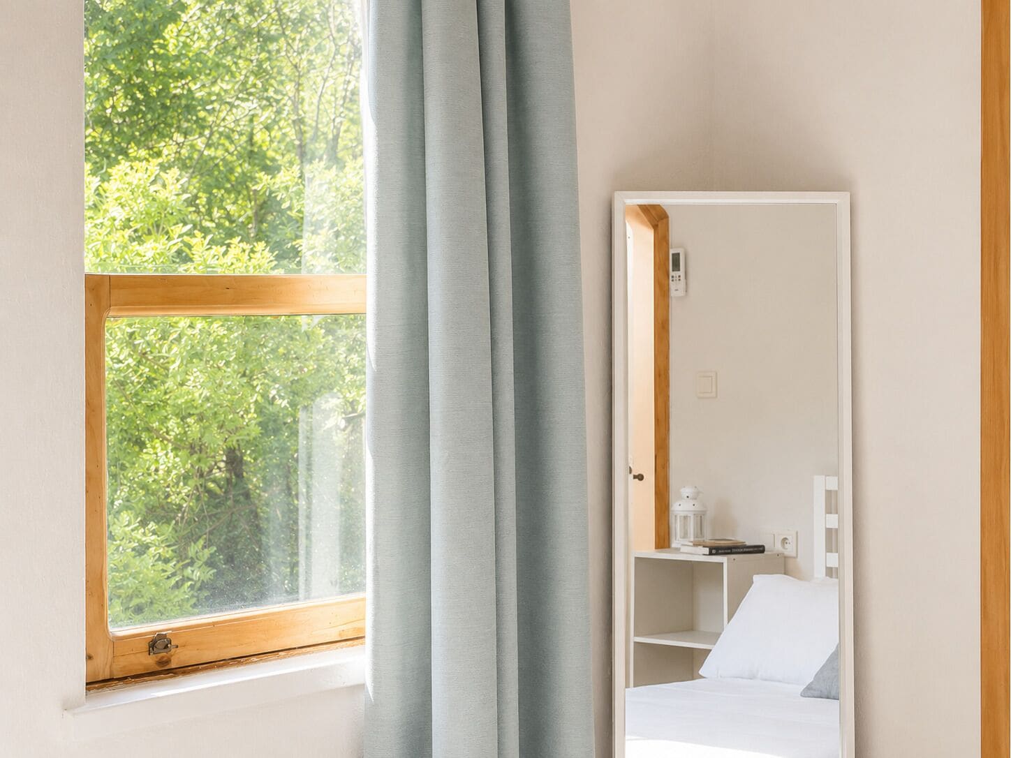 A room with a window, a bed, a bedside table, and a nightstand.