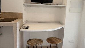 Cozinha com bancada, televisão e dois bancos.