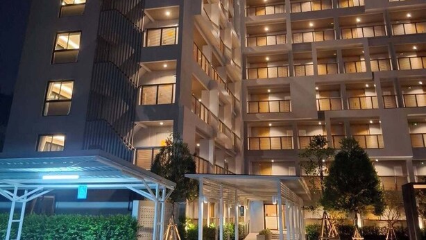 Un hôtel à plusieurs étages, doté de fenêtres illuminées et d’un parking couvert.