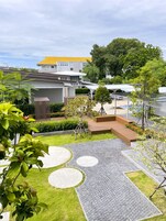 A modern outdoor area with a paved walkway, green lawns, and a building with a yellow roof.