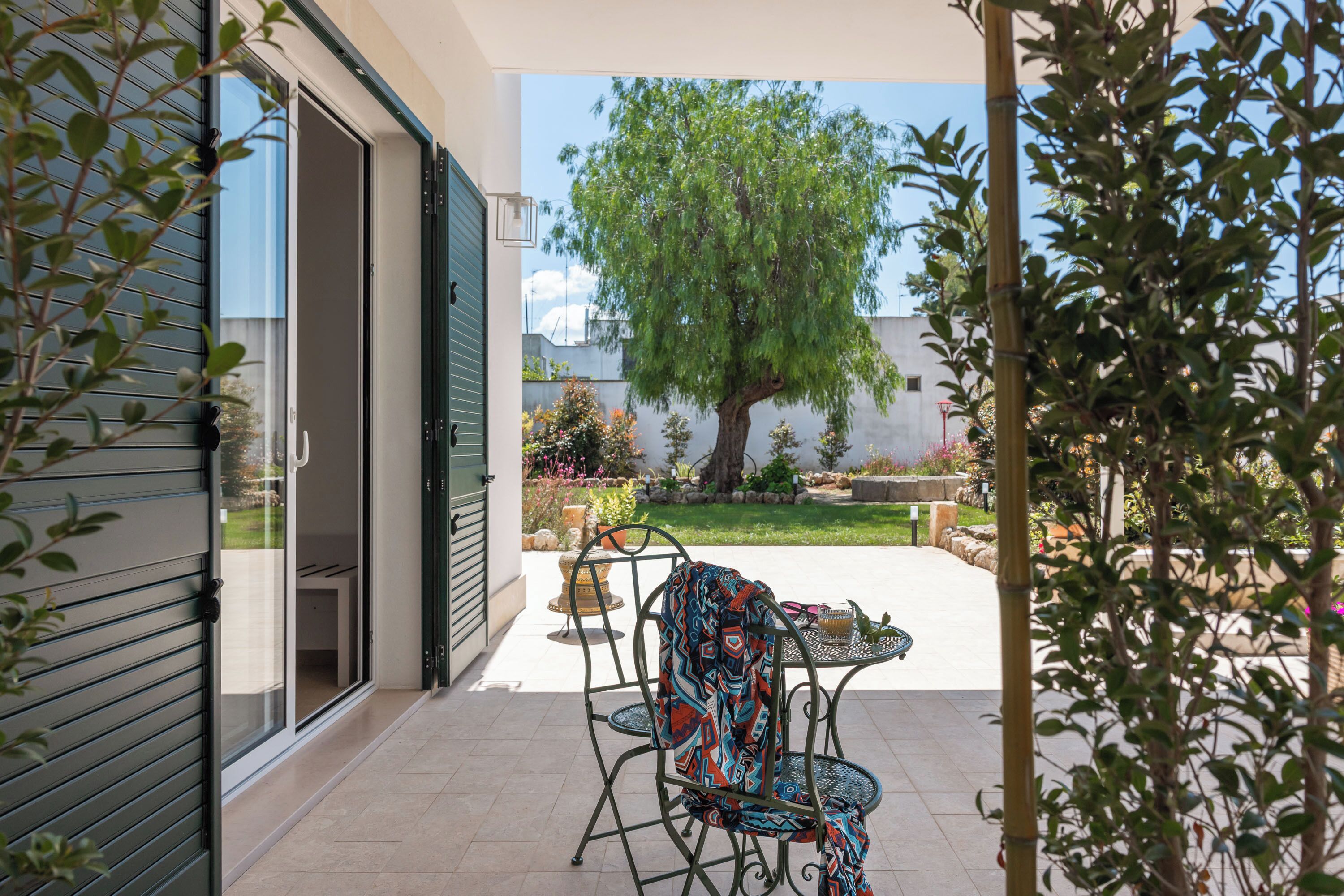 Une terrasse avec une table et des chaises, un arbre et un bâtiment doté d’une porte coulissante.