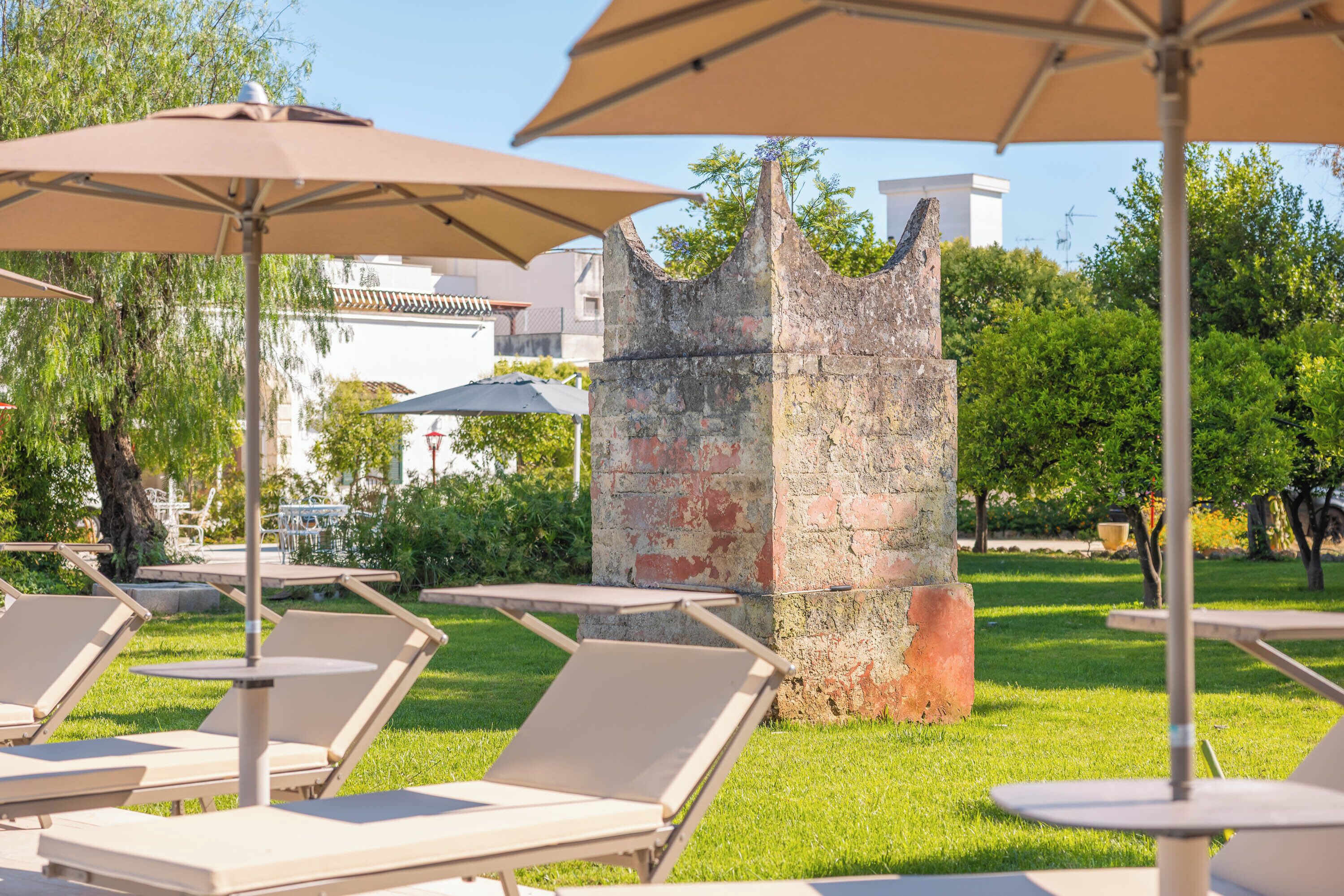 Outdoor seating with umbrellas, a stone structure, and greenery.