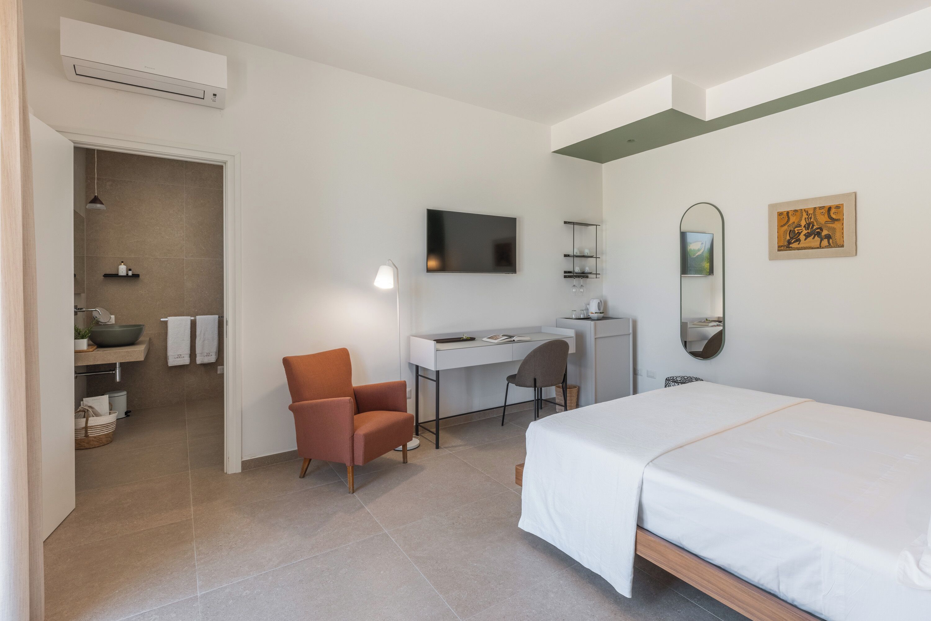 Ein modernes Hotelzimmer mit Bett, Schreibtisch, Stuhl und einem kleinen Badebereich.
