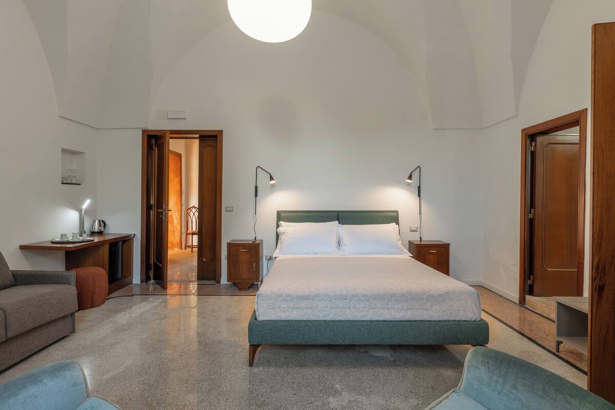 A bedroom with a large bed, bedside tables, a desk, and a chair.