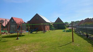 Un terrain de jeux avec des balançoires et un toboggan, entouré de bâtiments aux toits rouges.