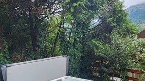 A hot tub on a wooden deck with a view of a forest and mountains in the background.
