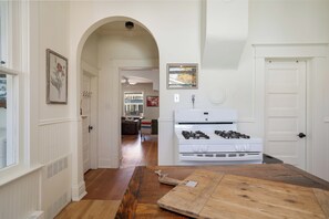 A kitchen with a white stove, wooden flooring, and a view into the dining area.