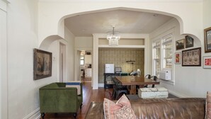 Una sala de estar amplia con un sofá de cuero, un sillón verde y una zona de comedor con candelabro.