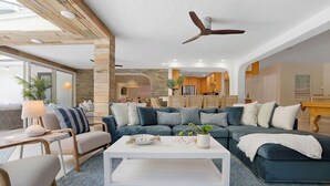 A modern living room with a sectional sofa, a white coffee table, and a ceiling fan. - Pool/Spa & Walk to the Beach Ping Pong Billiards (Palm Beach Shores)