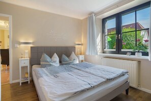 Una camera da letto con un letto, comodini, una finestra vista e una parete con un lampadario.