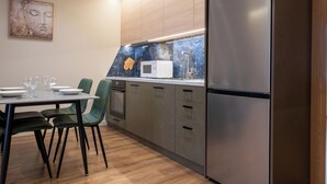 A modern kitchen with a dining table set for four, a microwave, and a stainless steel refrigerator.