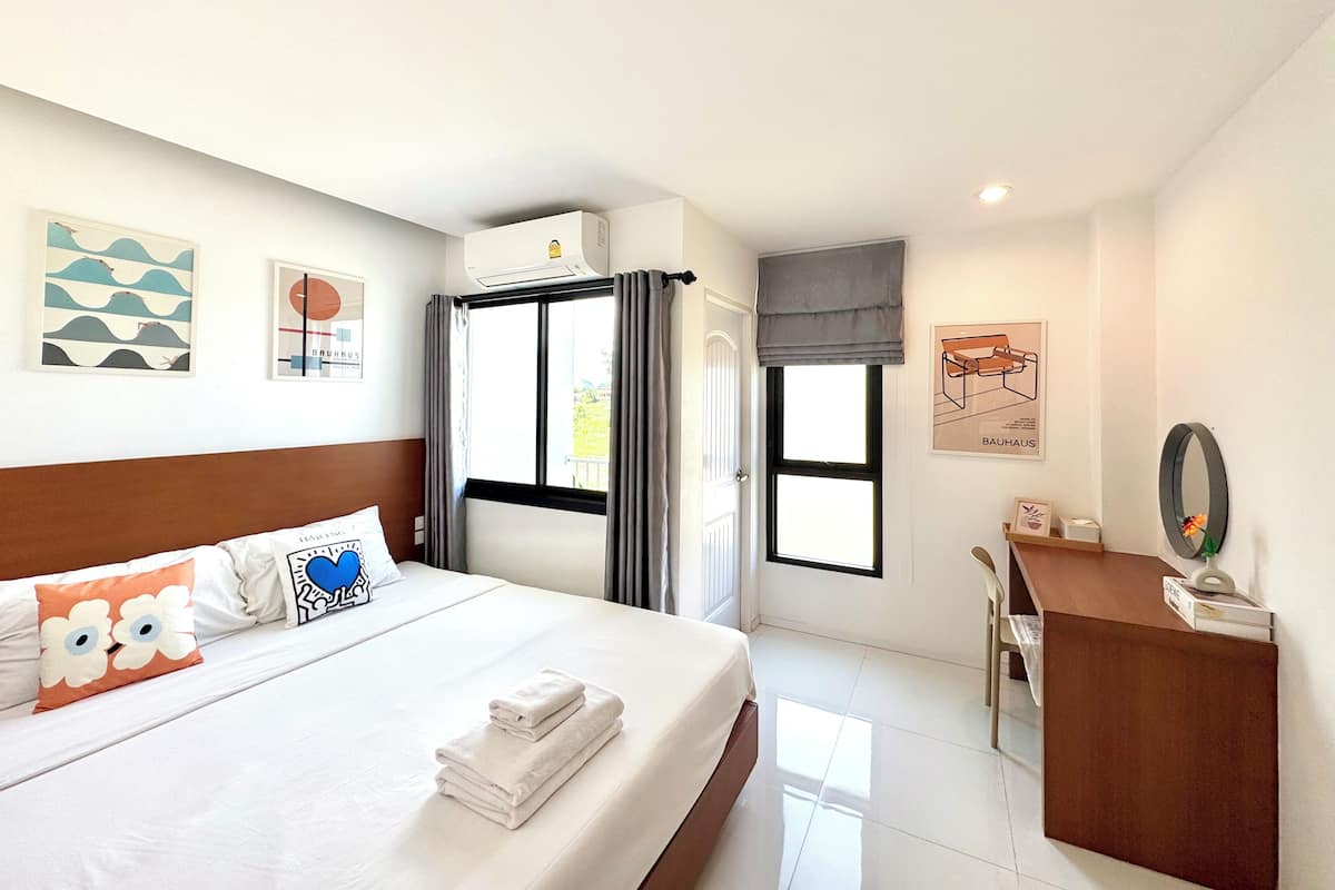 A hotel room with a bed, a desk, a mirror, and artwork on the walls.